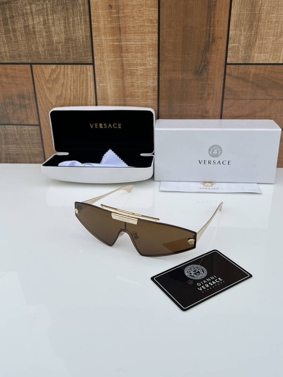 Versace shield sunglasses with a gold metal frame and dark grey/mirror gold lenses.